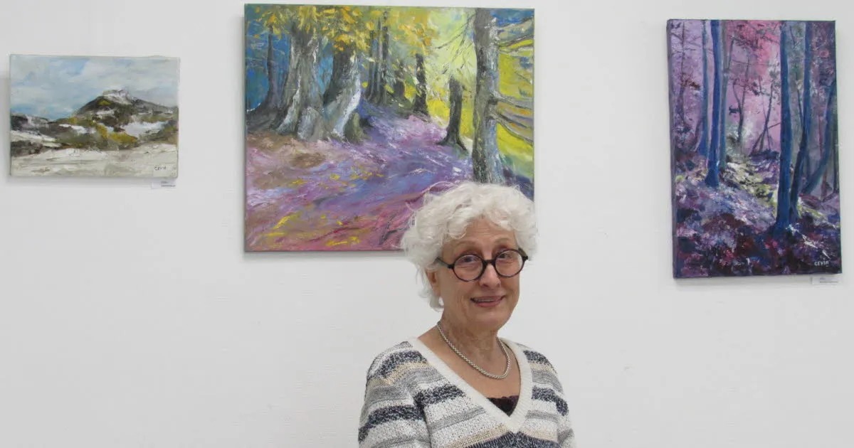 Cevia (Chantal Vigne) devant plusieurs de ses toiles lors d'une exposition